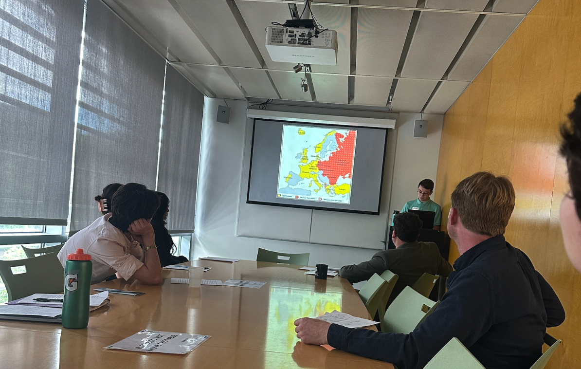 People watch a presentation with a projected red and yellow map of Europe