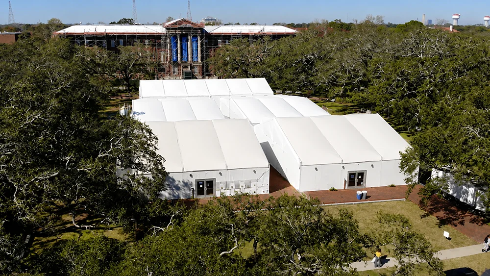 White modular tents on a green lawn with a grand columned building behind them.