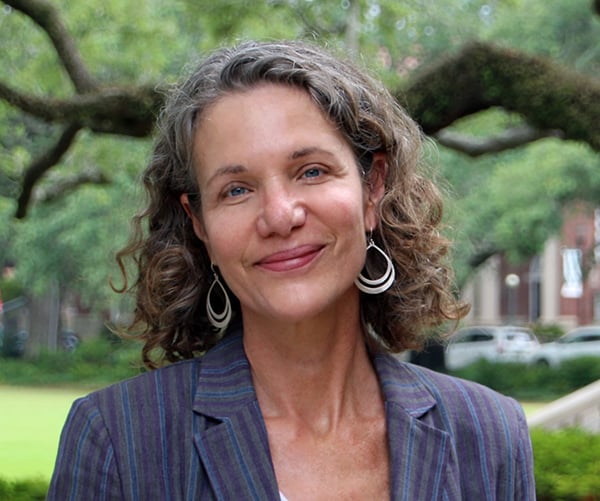 Photograph: Smiling woman with curly grey hair in a striped jacket, outdoors.