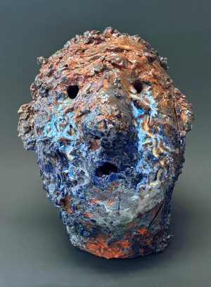 Sculpture of head with many colors and pocked skin