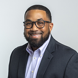 Professional portrait of a man in a suit with gentle smile.