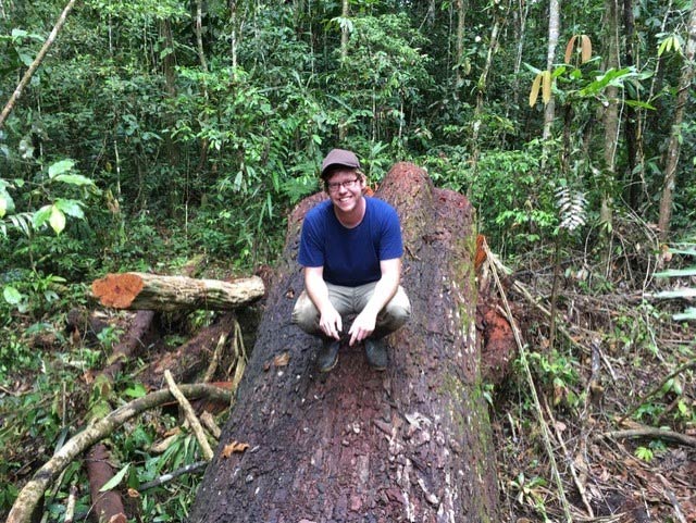 Ph.D. candidate in anthropology Travis Fink sitting on a tree trunk during a communal work party