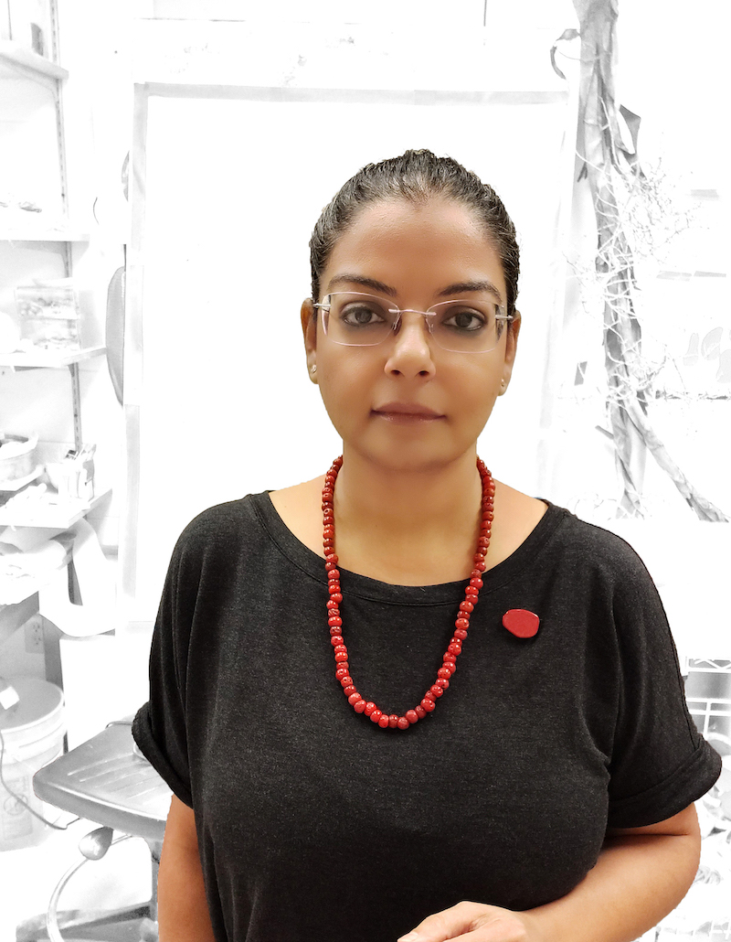 Portrait of artist Ina Kaur with a red bead necklace and pin