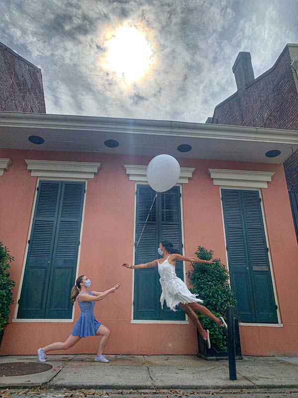 The Body Remembers. Two dancers with a balloon in front of a red house. 