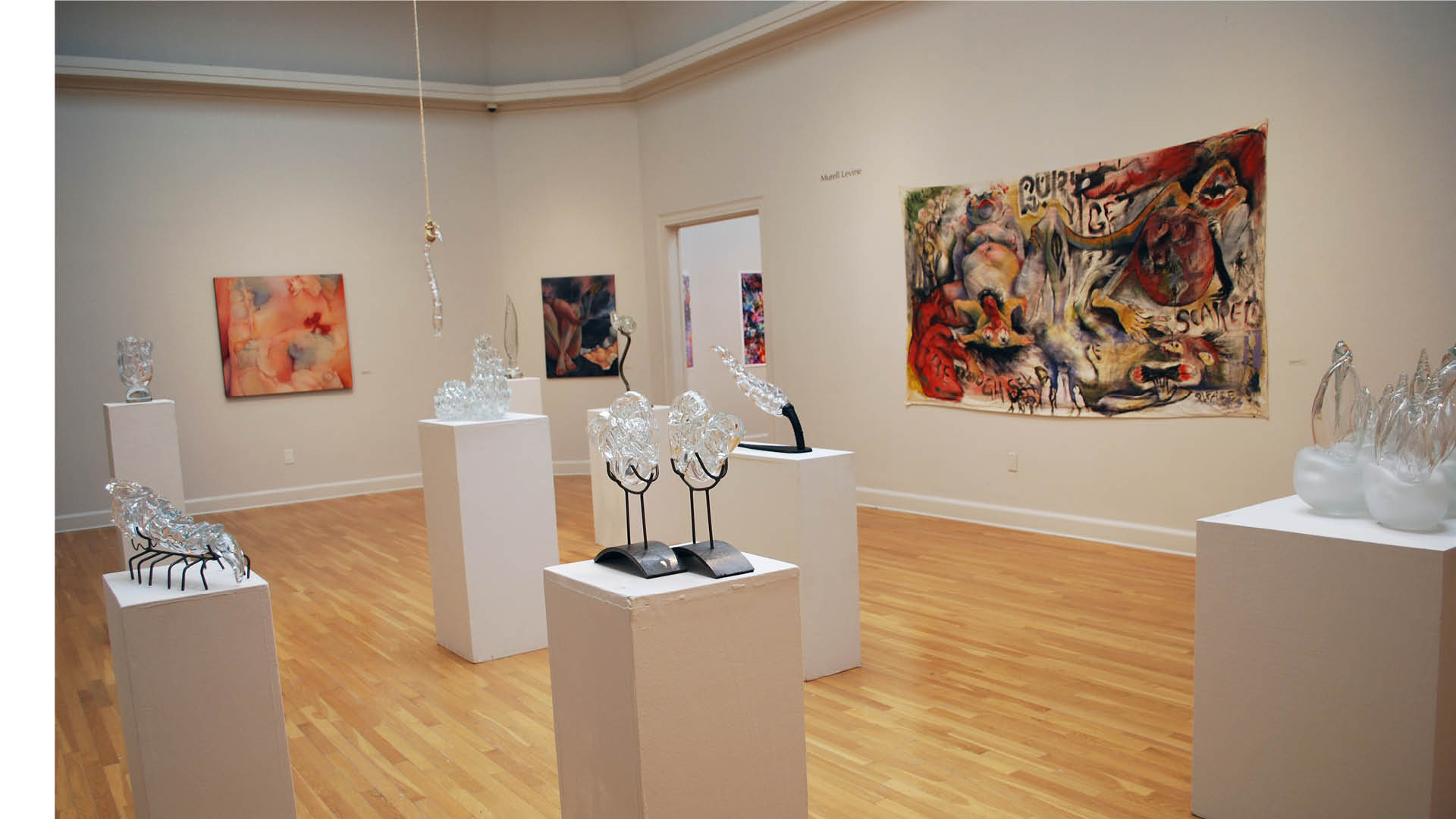 overview of gallery with glass sculpture by Leo Fine and paintings on canvas by Murell Levine