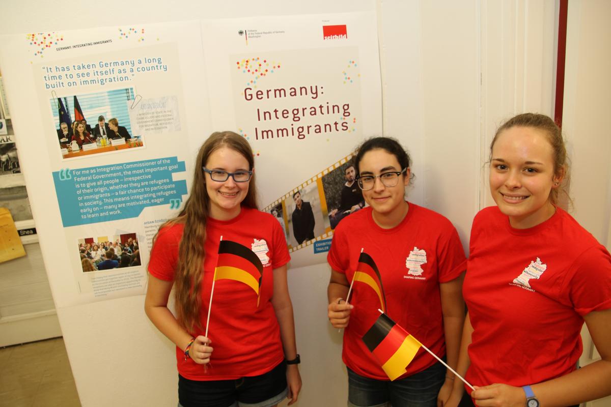 Three students with small German flags at the Integrating Immigrants exhibit