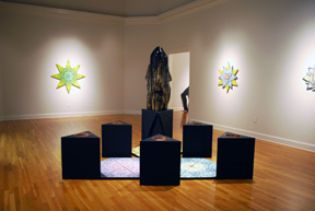 gallery view with star form illuminated on far wall and construction of six triangular pedestals