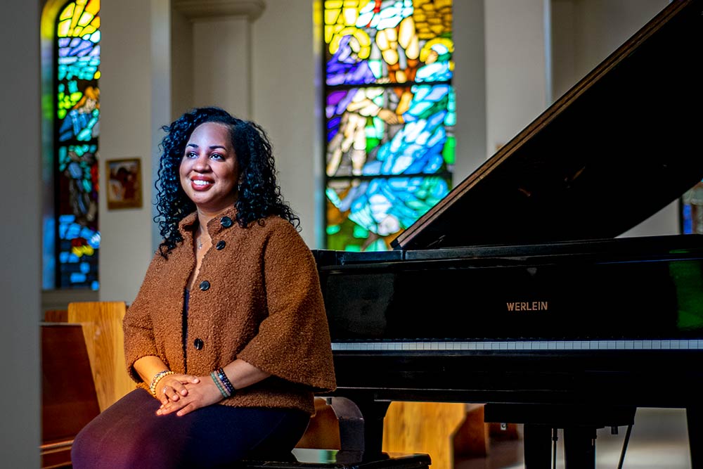 Courtney Bryan sitting at a grand piano in a church
