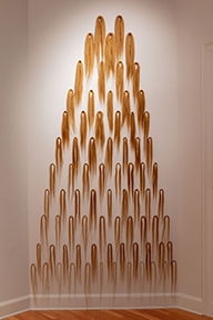 wall hung triangular sculpture made of light brown hair extensions