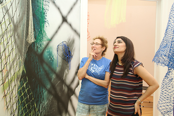 Artist Sally Heller looks onto the early stages of the installation with Sara Abbas