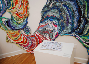 multi-colored crocheted wall hanging that meanders over two converging walls