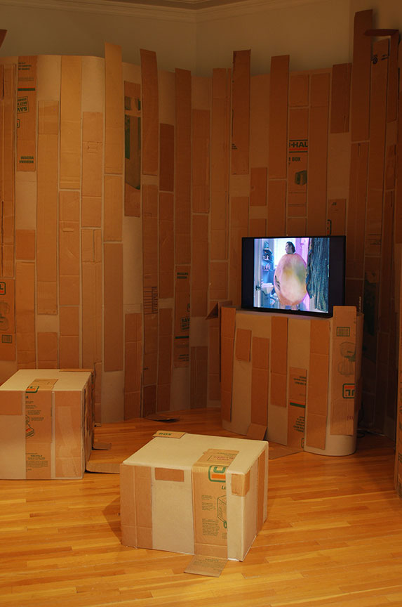 Peach Body Summer installation by Ellen Bull, with cardboard covered seats and monitor