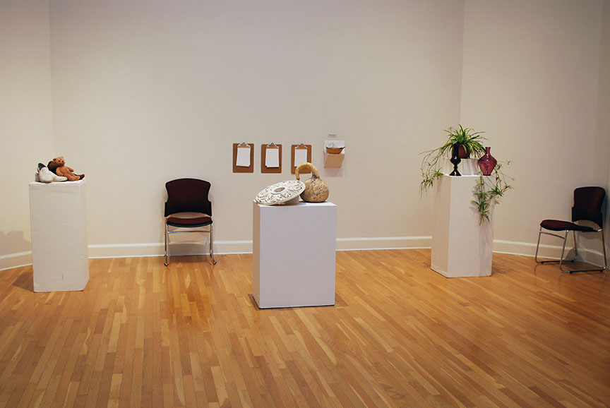 Overview of three still lifes in gallery with clipboards on wall