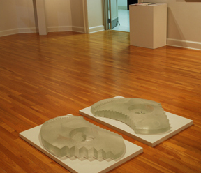 two cast glass forms on floor of gallery resembling footprints with stair motifs
