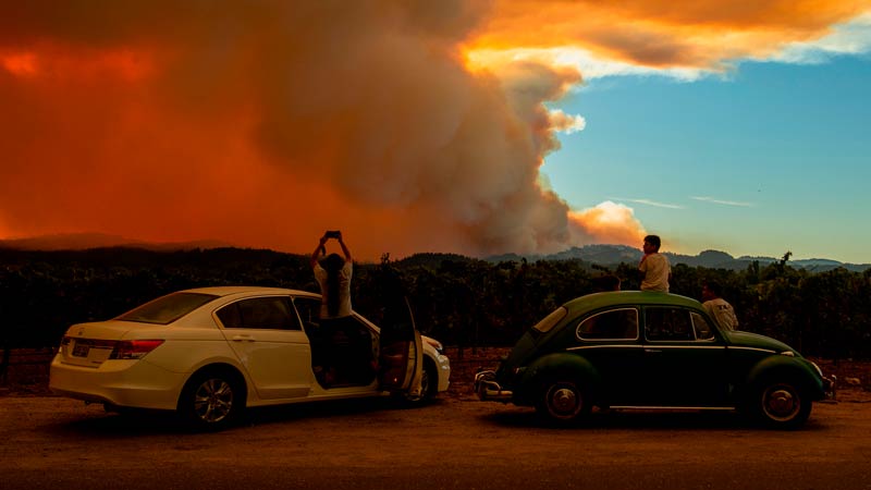 People next to cars watching sunset