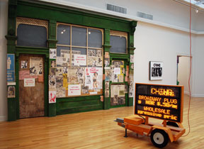 building facade installed and windows covered in posters, and an illuminated sign on wheels