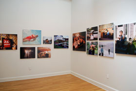 corner view of gallery with 12 side-by-side photographs installed