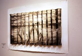 charcoal drawing depicting waterscape with accordion folds hung on wall 