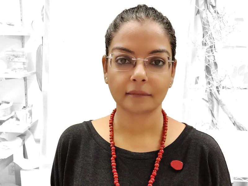 Portrait of artist Ina Kaur with a red bead necklace and pin