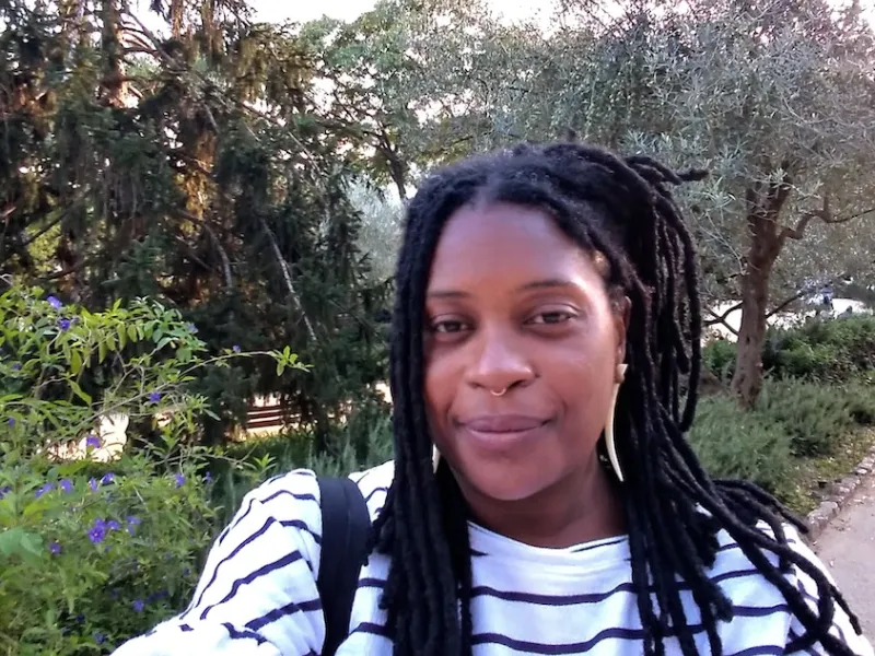 Z'etoile Imma in a Black and White Striped Shirt Against a Nature Background