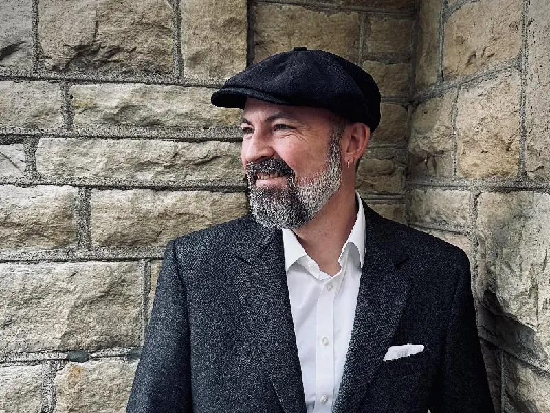 T.E. Winningham in a gray suit against a stone wall in a grey hat